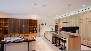 Eine moderne Küche mit Holzausstattung, einer zentralen Kochinsel mit Sitzgelegenheiten und einem eingebauten Backofen.