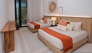 Ein Hotelzimmer mit zwei Betten, einem Holztisch, einer Lampe und einem großen Fenster mit Jalousien.