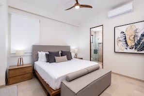 Ein modernes Schlafzimmer mit Bett, Nachttischen, Deckenventilator, großem Spiegel und einem gerahmten Kunstwerk an der Wand.