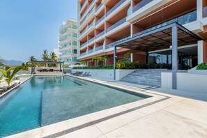 Ein modernes Hotel mit Schwimmbad, Außenbereich und einem mehrstöckigen Gebäude.