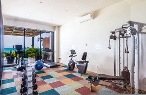 Ein Fitnessraum mit Trainingsgeräten, einer Bank und einem farbenfrohen Boden.