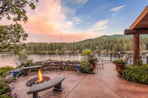 A lakeside patio with a fire pit, stone seating, and potted plants. - Riverfront Estate in Post Falls (Post Falls)