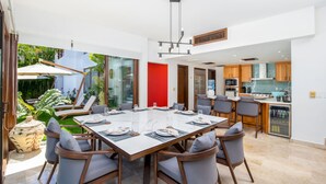 Un comedor moderno con una mesa grande, sillas y una cocina al fondo.