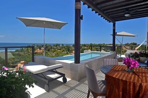 A rooftop terrace with a pool, lounge chairs, umbrellas, and a table with flowers. - Lux 3 Bed Condo With Ocean View Pool Houskeeping (Punta de Mita)