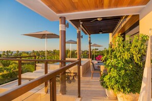 A rooftop terrace with outdoor seating, umbrellas, and a view of the landscape. - Lux 3 Bed Condo With Ocean View Pool Houskeeping (Punta de Mita)
