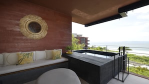 Ein Balkon mit Meerblick, eine Couch mit Kissen und eine runde Wanddekoration.