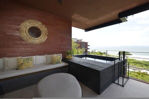 Ein Balkon mit Meerblick, eine Couch mit Kissen und eine runde Wanddekoration.