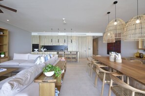 Ein modernes Wohnzimmer mit Sofa, Esstisch und einer Küche im Hintergrund.
