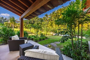 A covered outdoor seating area with wicker furniture and a lush garden backdrop. - Serene Luxury - Private Pool Ocean View Cook Lagos 16 (Punta de Mita)