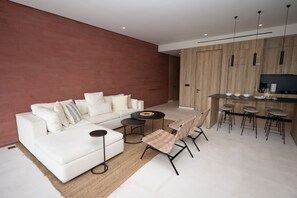 Ein modernes Wohnzimmer mit einem weißen Sofa, einem Couchtisch und einem Essbereich mit Barhocker.