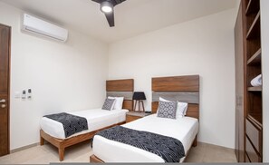 Ein Schlafzimmer mit zwei Betten, einer Klimaanlage, einer Nachttischlampe und einem Kleiderschrank.