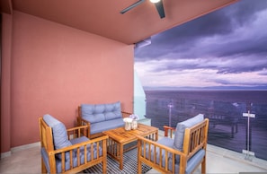 Ein Balkon mit Blick auf das Meer, einem Holztisch und zwei Sofas.