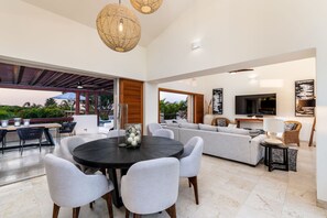 A modern living room with a round table, sofas, and a TV. - 4BR Las Palmas Villa Premier Golf Private Pool Cook 3 Golf Carts - Las Palmas 21 Casa Rayo De Sol (Punta de Mita)
