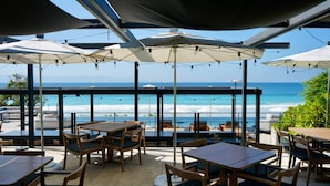 An outdoor seating area with tables and chairs, umbrellas, and a view of the ocean. - Naya 3302 Tower III in Punta de Mita (Punta de Mita)