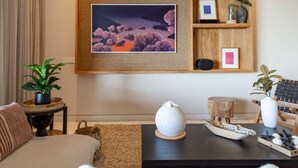 A living room with a sofa, a coffee table with decorative items, a framed picture on the wall, and a potted plant. - Naya 3302 Tower III in Punta de Mita (Punta de Mita)
