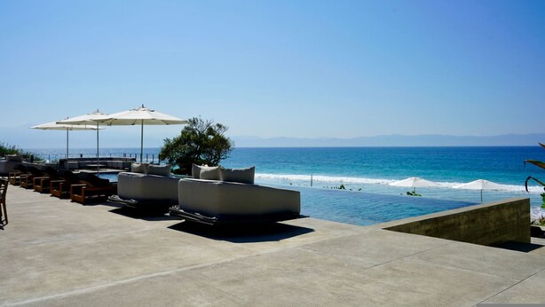 A poolside area with lounge chairs and umbrellas, overlooking the ocean. - Naya 3302 Tower III in Punta de Mita (Punta de Mita)