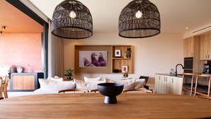 A modern dining area with a wooden table and chairs, a black bowl centerpiece, and two black hanging light fixtures. - Naya 3302 Tower III in Punta de Mita (Punta de Mita)