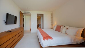 A bedroom with a bed, a TV mounted on the wall, a wooden dresser, and a hallway leading to another room. - 3 Bed 3 5 Bath Condo With Hsk Pool Ocean View (Punta de Mita)