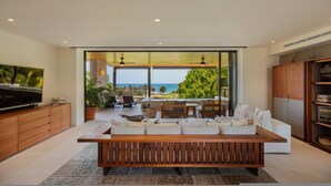 A modern living room with a large wooden bench, a television, and a view of the ocean. - 3 Bed 3 5 Bath Condo With Hsk Pool Ocean View (Punta de Mita)
