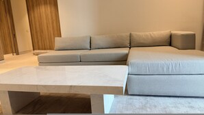 Un soggiorno moderno con un divano componibile, un tavolino in marmo e un pavimento in legno.