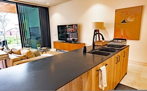 Eine moderne Küche mit einer großen Kochinsel, einem integrierten Fernseher und einem Essbereich mit Sofa und Tisch.