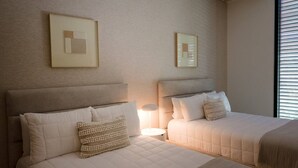 Ein Hotelzimmer mit zwei Betten, einem Nachttisch, einer Lampe und gerahmten Kunstwerken an der Wand.