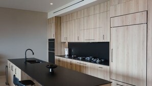 Eine moderne Küche mit einer zentralen Kochinsel, Barhocker und Holzschränken.