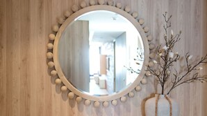 Ein Holzkonsolentisch mit einem runden Spiegel, einer Vase mit Zweigen und zwei dekorativen Schalen.