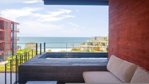 Un balcon avec vue sur la mer, une piscine et un bâtiment à la façade rouge.