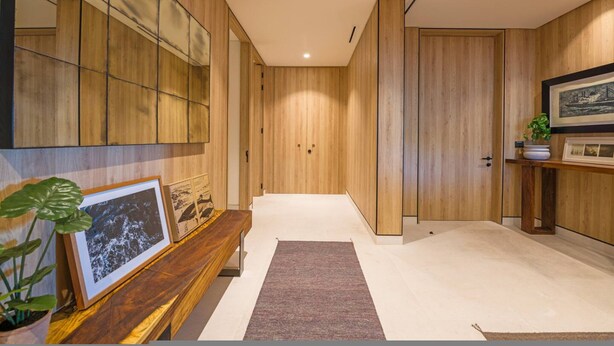 Un couloir moderne avec un lambris en bois, un banc, des tableaux encadrés et une plante en pot.