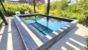 A rectangular swimming pool with a wooden deck, surrounded by lush greenery and a pergola structure. - Naya 4101 Tower IV in Punta De Mita (Punta de Mita)