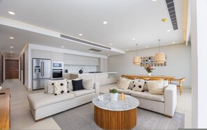 A modern living room with a sofa, coffee table, and kitchen in the background. - 4-bed Beachfront Lux Apartment (Bucerías)