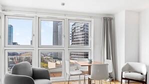 Ein modernes Wohnzimmer mit großem Fenster, einem Esstisch und zwei Stühlen.