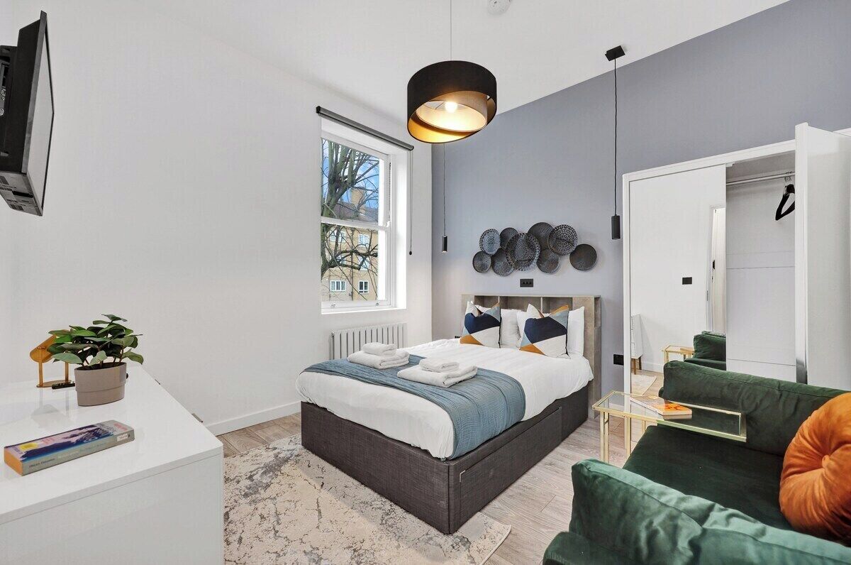 A modern bedroom with a bed, bedside table, and a green sofa.