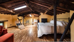 An attic bedroom with a wooden ceiling, a bed, a chair, and a suitcase. - Deluxe View Apartment in Borgo di Matraia (Capannori)