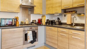 Een moderne keuken met houten kastjes, een roestvrijstalen fornuis en een inbouwoven.