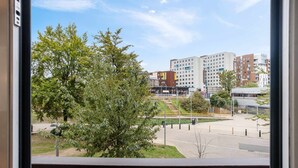Uitzicht vanaf een balkon met een complex van gebouwen op de achtergrond, waaronder een meerhoog gebouw met een opvallende geel-bruine gevel.
