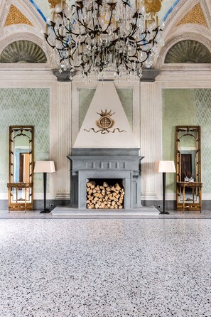 A grand room with a fireplace, two mirrors, a chandelier, and a patterned floor. - Giotto Luxury Apartment Villa Guinigi (Capannori)