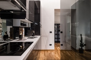 A modern kitchen with a black stove, white countertops, and a wooden floor. - Giotto Luxury Apartment Villa Guinigi (Capannori)