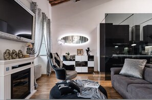 A modern living room with a fireplace, a sofa, a dining area, and a kitchen. - Giotto Luxury Apartment Villa Guinigi (Capannori)