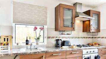 A modern kitchen with a granite countertop, stainless steel appliances, and wooden cabinets.