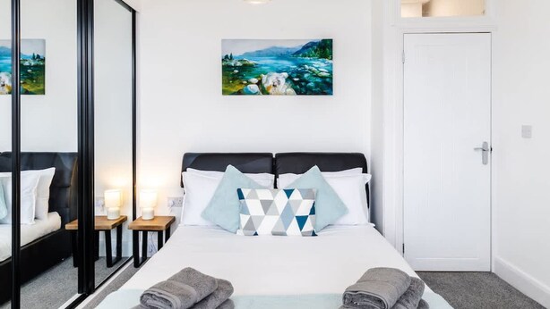A hotel room with a bed, a painting, a mirror, and a door. - 1-min Walk to High St 3-min to Mumbles Beach (Swansea)