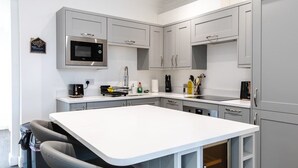 A modern kitchen with grey cabinets, a white countertop, and a built-in microwave. - 1-min Walk to High St 3-min to Mumbles Beach (Swansea)
