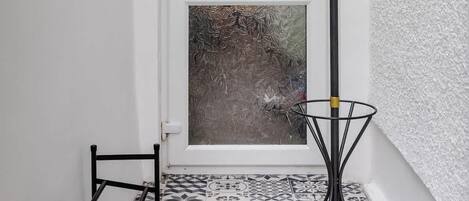 A room with a white door, a black metal rack, and a black metal stand with hooks.