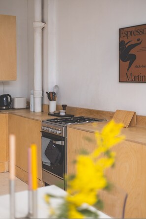 A kitchen with a gas stove, oven, and a wooden countertop. - Modern Flat in the Heart of Bethnal Green (London)