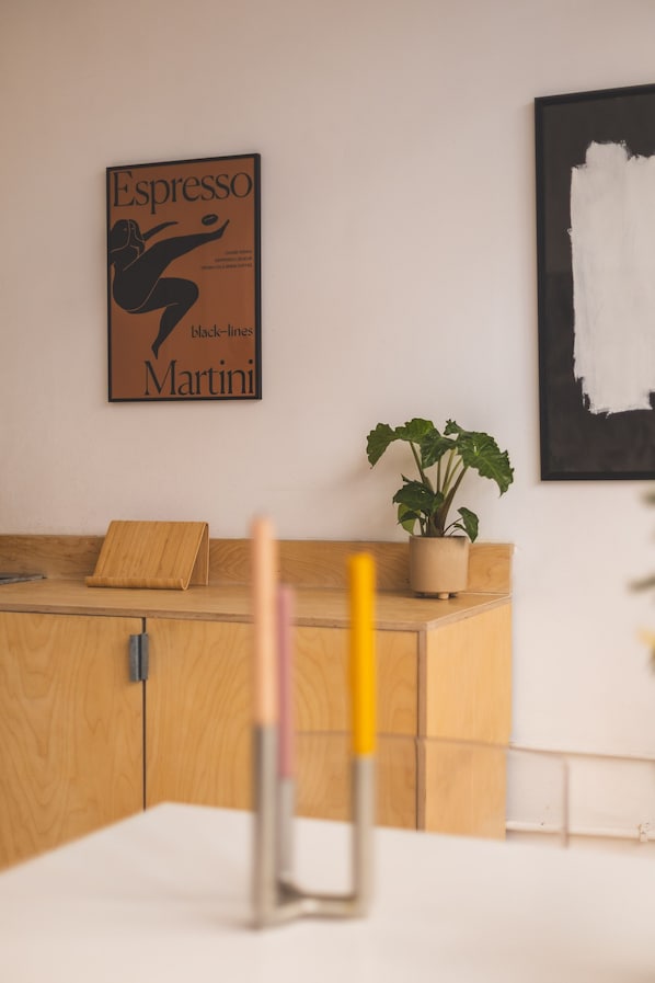 A wooden desk with a plant, a poster, and a pen holder. - Modern Flat in the Heart of Bethnal Green (London)