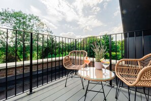 A balcony with wicker chairs, a glass table, and a potted plant. - Omega Acton Top Floor (London)