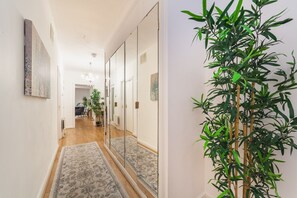 A hallway with a patterned rug, a mirror, and a bamboo plant. - Spacious Modern 3 Beds 3 Baths in Finchley (London)