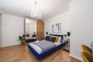 Ein modernes Schlafzimmer mit einem großen Bett, einer Kristallleuchter, einem Spiegel und einem Gemälde an der Wand.