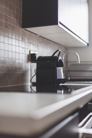 A kitchen with a countertop, a black appliance, and a tiled backsplash. - Spacious Modern 3 Beds 3 Baths in Finchley (London)